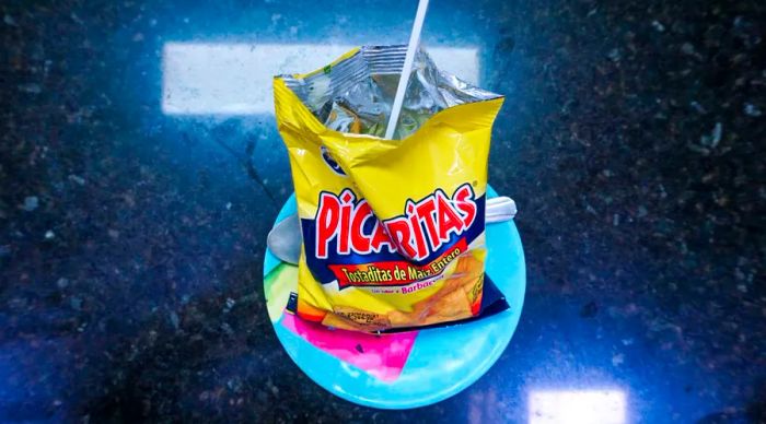 A plate featuring a bag of chips with a fork nestled inside.