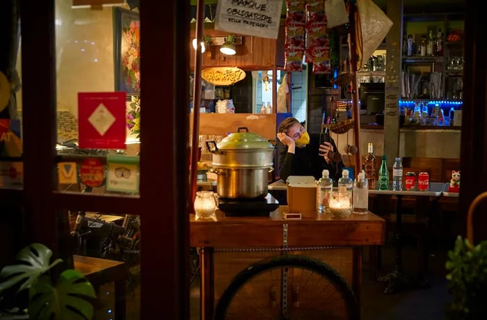 A restaurant employee waits for customers at a closed establishment offering takeaway food and drinks.