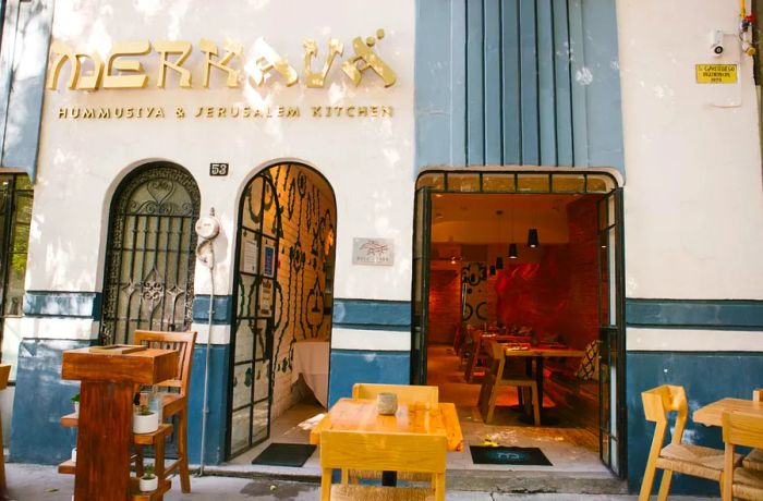 The entrance of a restaurant featuring outdoor tables.