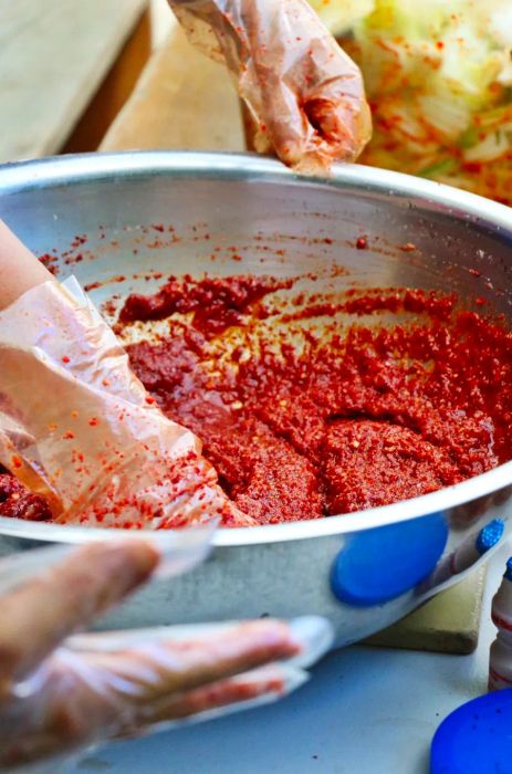 Gloved hands combine a chili paste marinade in a large bowl