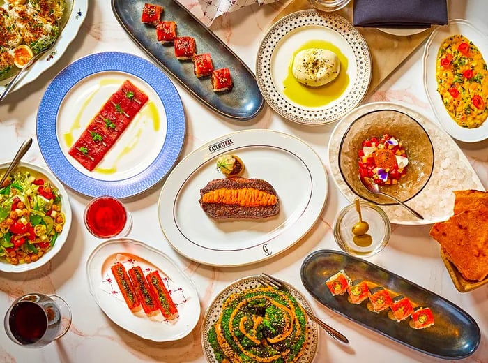 An aerial view of a table adorned with a variety of dishes, including steak, sushi, and salads.