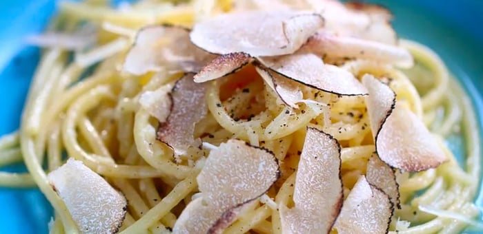 A bowl of pasta adorned with shaved truffles