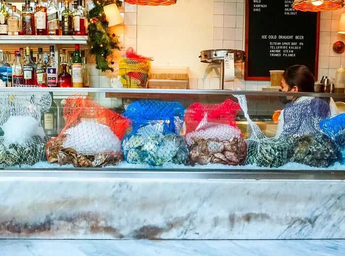 Vibrant bags of oysters displayed on ice at the restaurant bar.