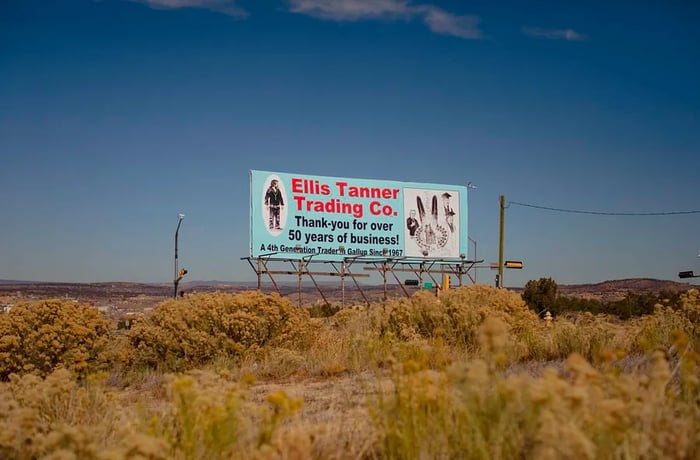 A billboard amidst the scrub brush promotes the Ellis Tanner Trading Company, celebrating over 50 years in operation.