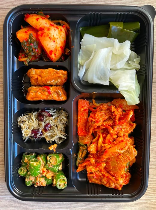 A black container filled with various Korean dishes.