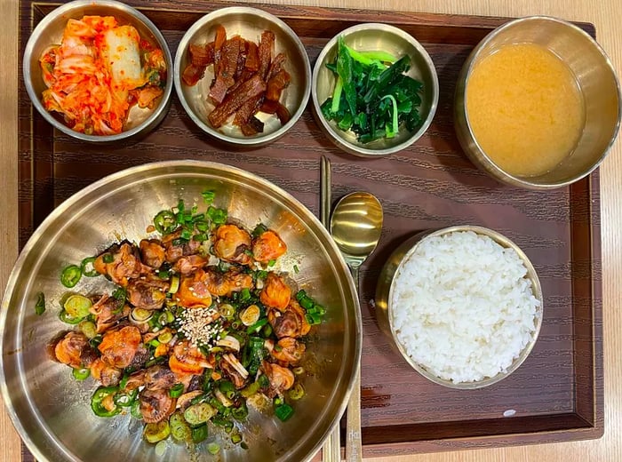 A bibimbap set presented in copper bowls, complete with kimchi, spinach, radish, and bean paste soup.