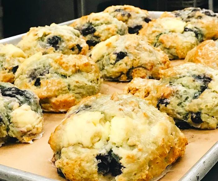 A full sheet pan loaded with blueberry scones in a kitchen setting