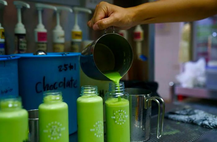 A green matcha drink is being poured into bottles.