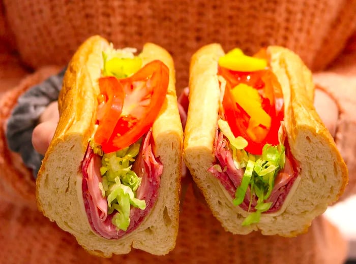 A person holds up a half-cut Italian hoagie.