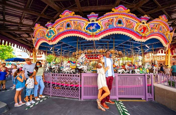 Two families gather outside a carousel.