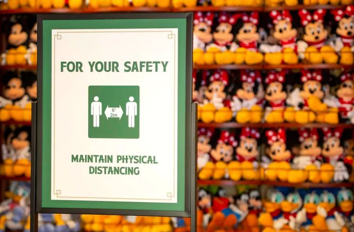 A social distancing sign in front of plush Minnie Mouse toys.