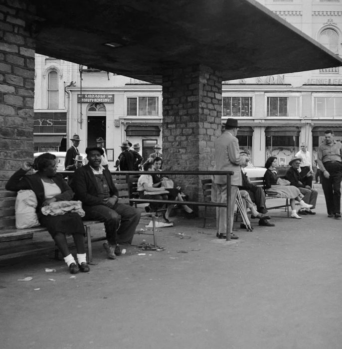 A Black couple sits on a bench, separated from white patrons by a visible barrier.