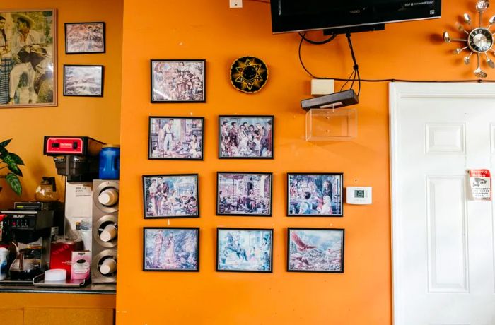 An orange wall adorned with a collection of framed photos next to a beverage vending machine.