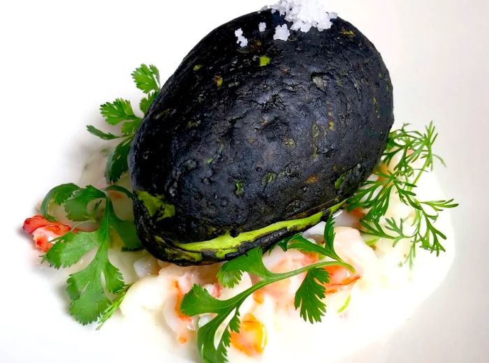 A beautifully garnished halved avocado served on a white plate.