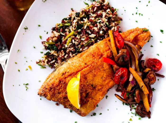 A fillet of trout accompanied by sautéed vegetables and wild rice.