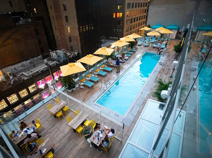 An outdoor swimming pool adorned with yellow umbrellas and teal loungers.