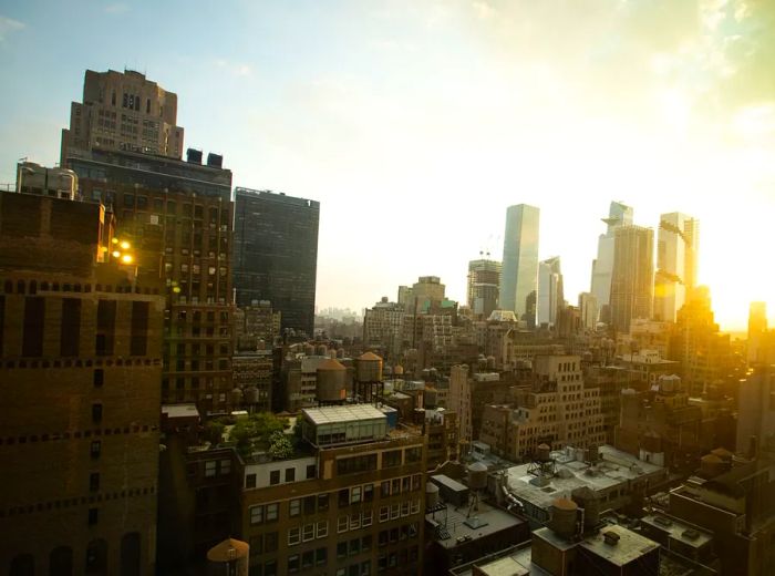 The skyline of New York City illuminated by the sunset in the background.