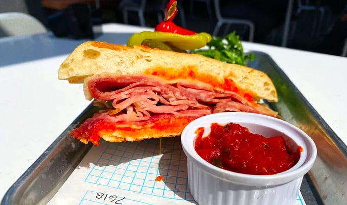 A towering ciabatta sandwich displayed on a metal tray.