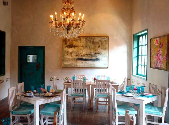 A dining area featuring white tables and chairs adorned with aqua cushions and accents.