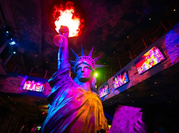 A towering statue of liberty cradles a massive margarita that projects flames.