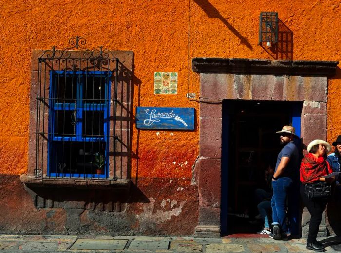 People wearing cowboy hats gather outside an orange building.