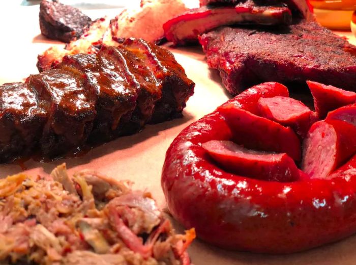 A paper tray overflowing with chopped sausage, ribs, pulled pork, and meatloaf.