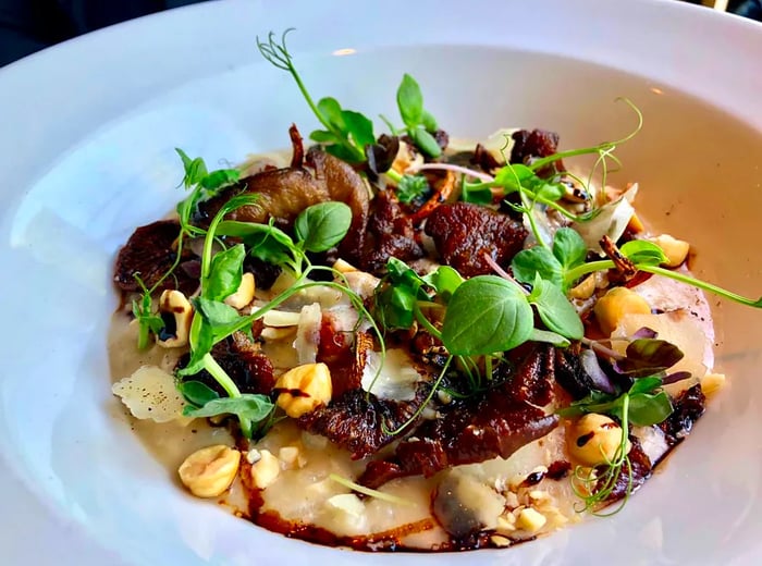 A dish of risotto garnished with mushrooms and fresh herbs.