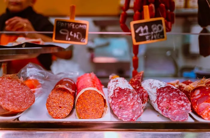 A display of sliced sausages on a butcher's counter.