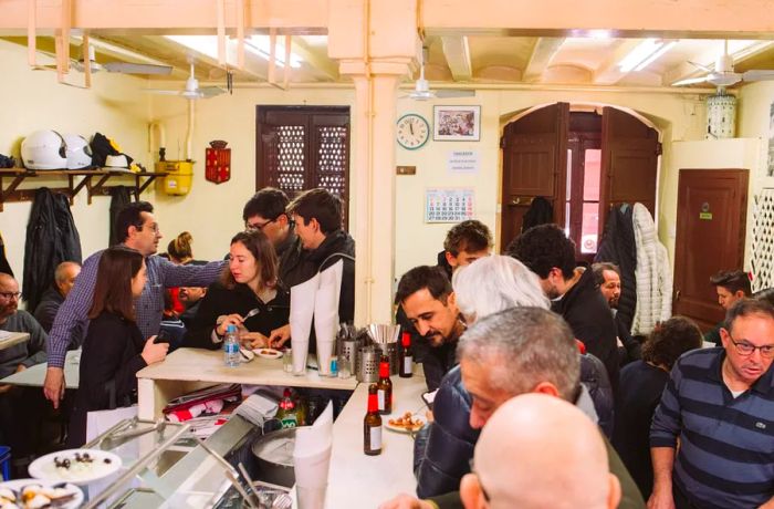 A bustling bar during the day with wooden doors slightly ajar.