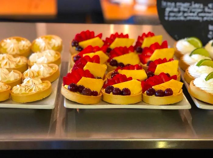 A display of fruit-topped tarts arranged on a bakery counter.