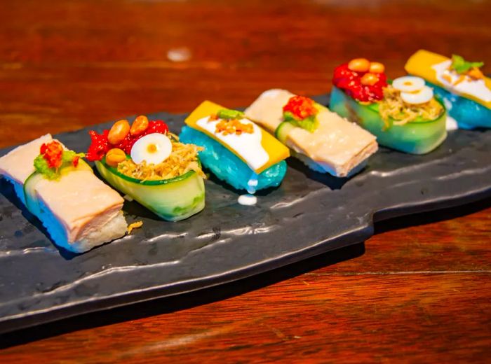 Artfully arranged, intricate sushi rolls presented on a long slate.