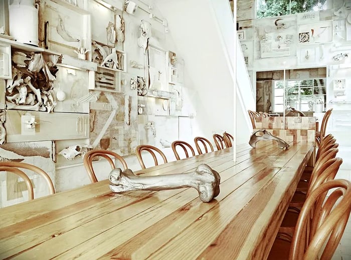 A long wooden table adorned with bones as centerpieces, set against a backdrop of whitewashed decor