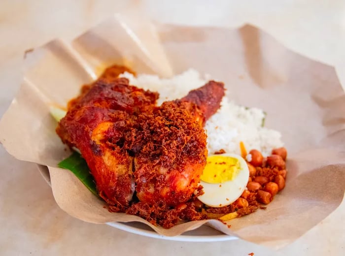 A generous portion of ayam goreng rempah served atop a plate of nasi lemak.