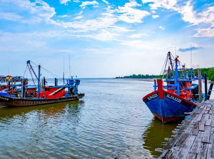 Fishing boats rest at jetties, set against a vast water expanse under clear blue skies.