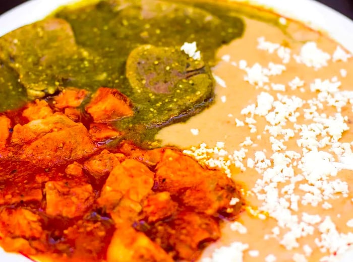 A vibrant plate featuring chicharrón and lengua dressed in a variety of sauces