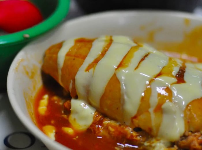 A lonche drenched in generous amounts of creamy sauce, resting in a flavorful pool of salsa.