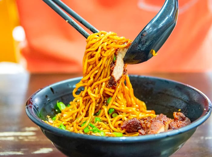 Chopsticks and a spoon lift a serving of chili pan mee.