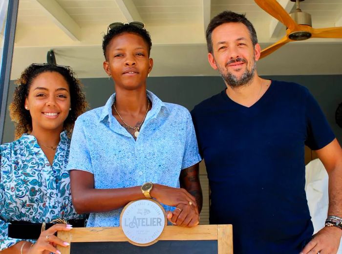 Three members of the L’Atelier Bar crew stand proudly at the entrance of their restaurant