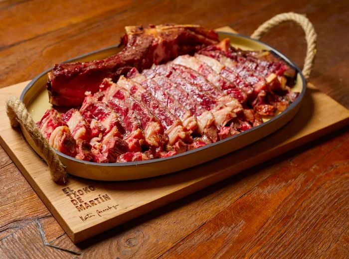 A large, sliced steak presented on a metal tray with sturdy rope handles