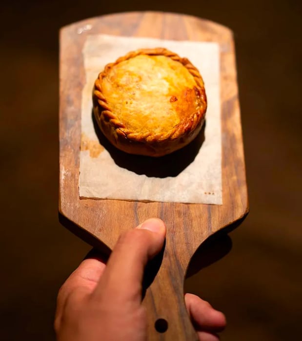 A beautifully crimped pastry presented on a rustic wooden board