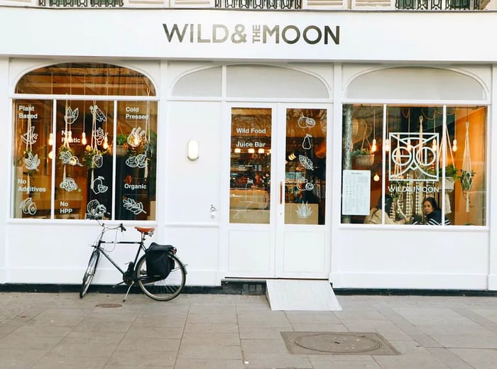 The exterior of a white restaurant adorned with illustrated designs on the windows, with a bike parked out front.