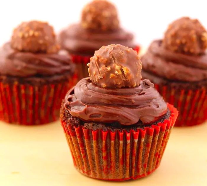 Chocolate cupcakes adorned with chocolate candies on top.