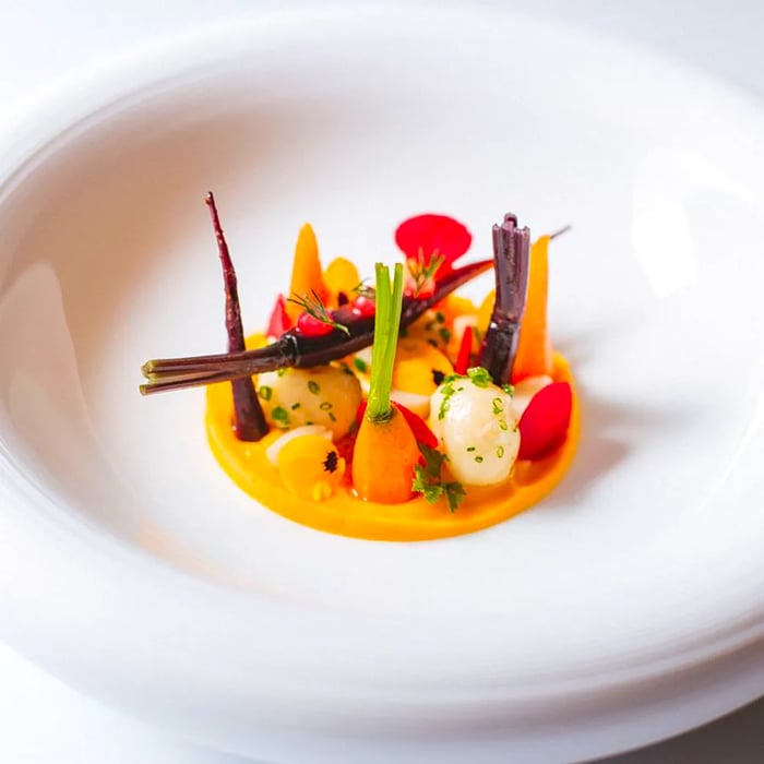 Intricately arranged carrot pieces swimming in a flavorful sauce