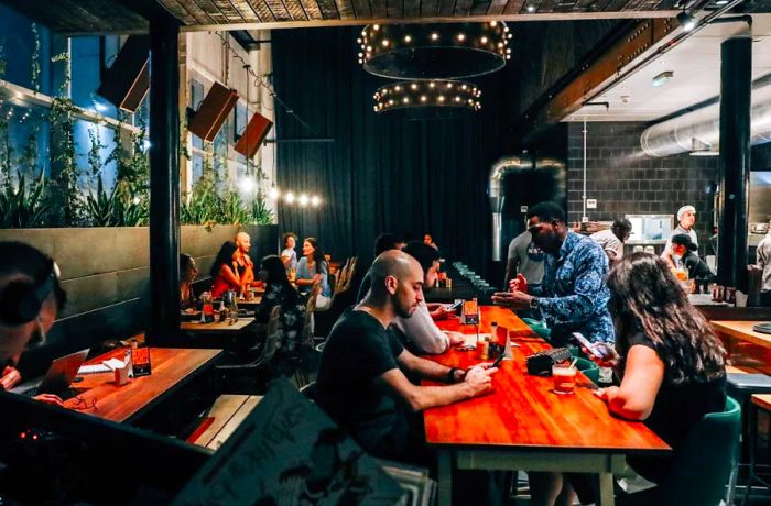 The interior of the café features diners gathered around long communal wooden tables.