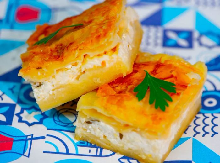 A thick su borek, generously stuffed and garnished with parsley, placed on a decorative background.