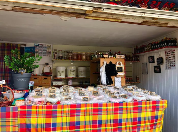 A quaint open-air shop displays bags of spices beneath chalkboard signs.