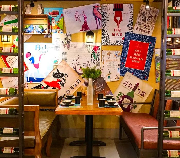 A cozy restaurant booth separated by a room divider, adorned with posters and a table elegantly set for dinner