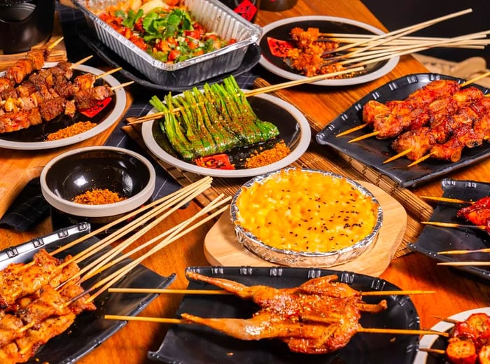 A table laden with an assortment of skewers, featuring meats, shrimp, and vegetables.