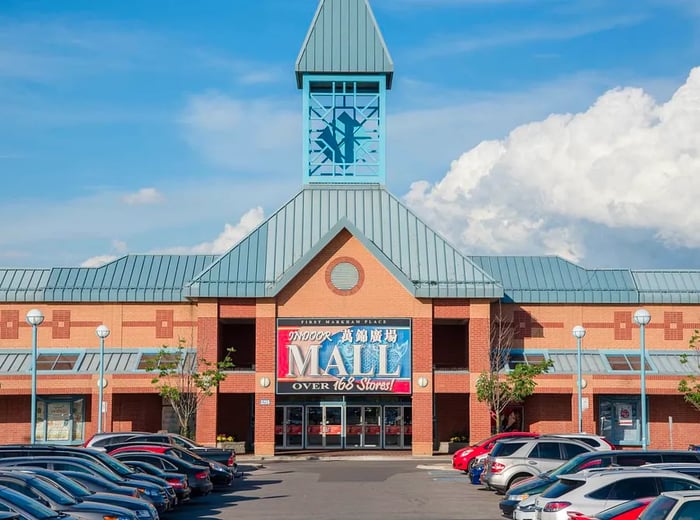 A mall facade featuring a prominent sign and a bell tower set against a clear blue sky