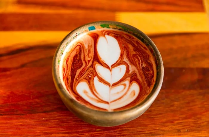 A frothy, latte-like design graces a chocolate drink served in a clay cup.